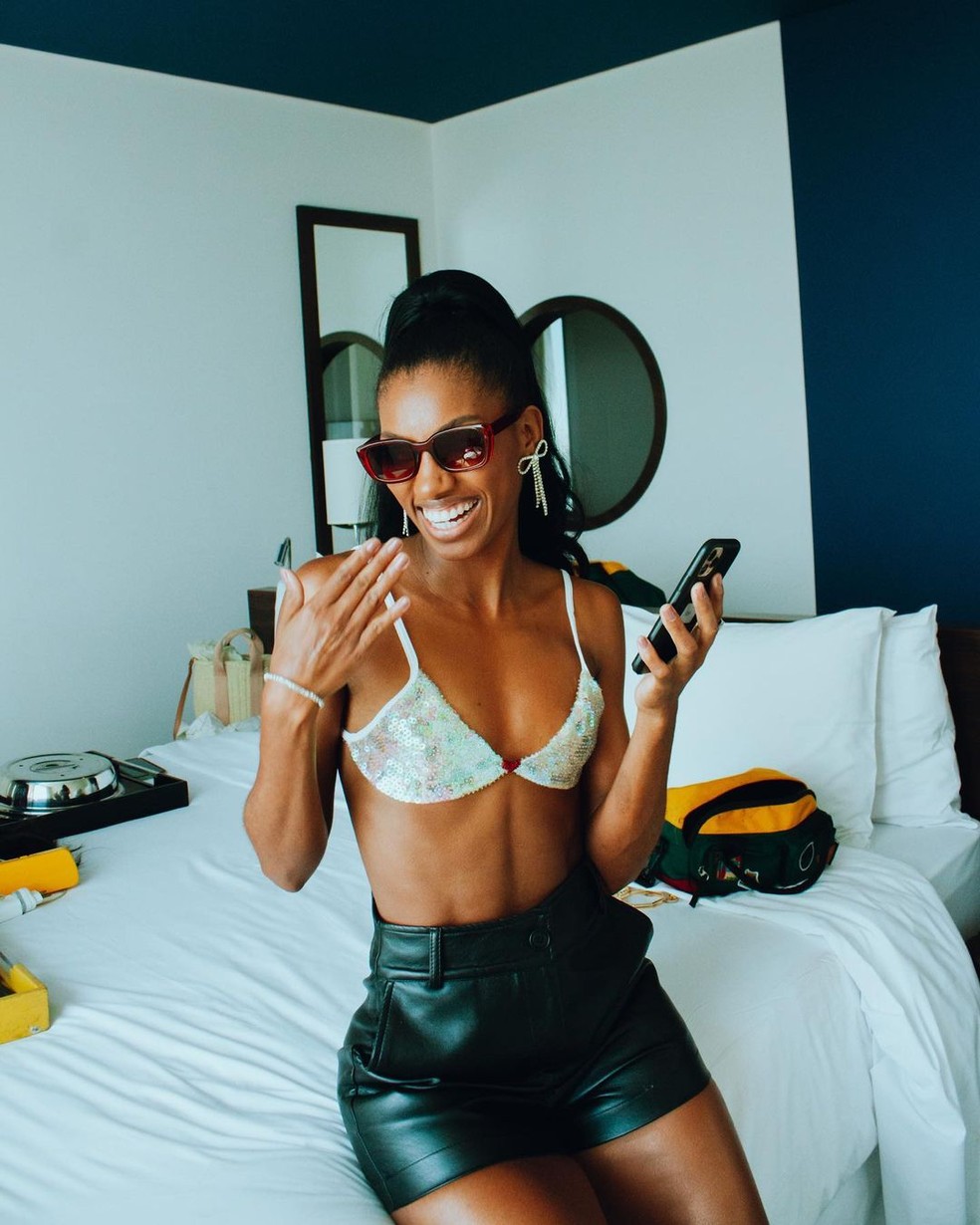Tina posa sorridente sentada em cama de hotel — Foto: Reprodução/Instagram