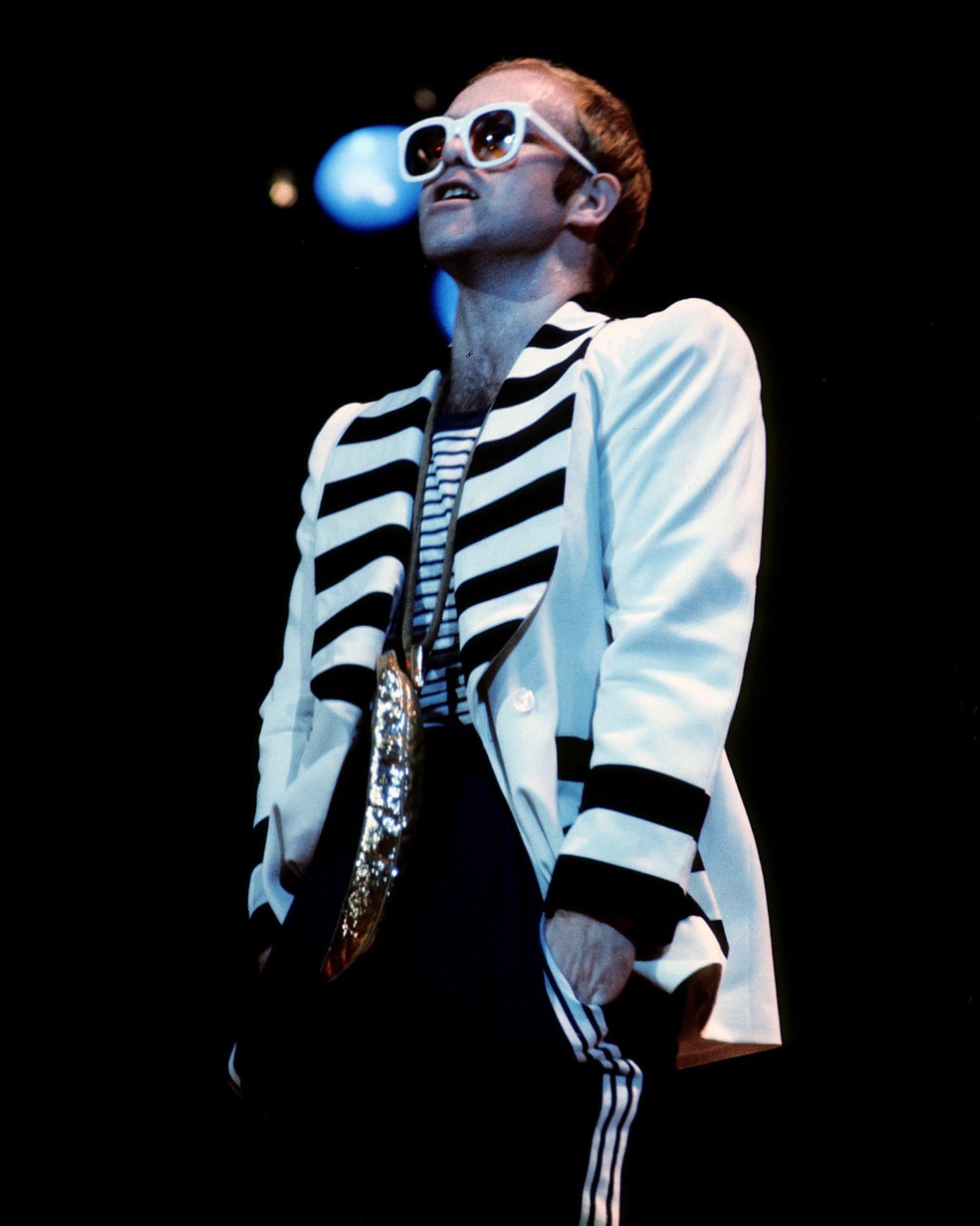 Elton John: óculos de sol extravagantes, termos festivos e diversos acessórios dão o tom do estilo glamouroso do músico — Foto: Getty Images