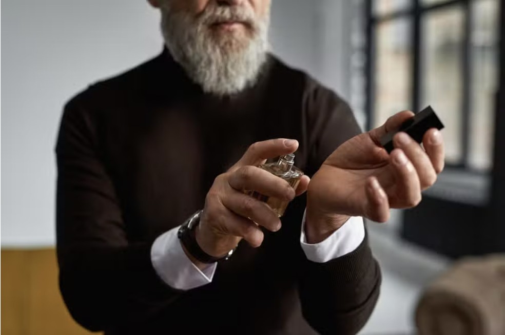 5 perfumes para o homem com mais de 50 anos receber mais elogios. Um homem grisalho passando perfume.  Foto: Getty Images